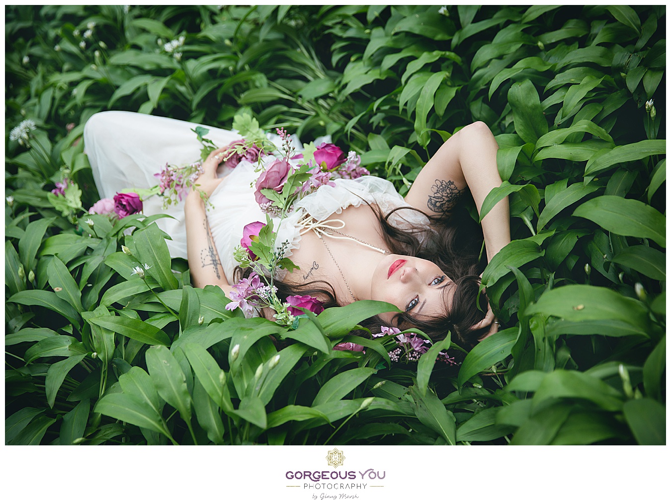Feminine white tulle dress, lying in a bed of green wild garlic with pink flowers | Divine feminine goddess boudoir photoshoot | Gorgeous You Photography | North Yorkshire