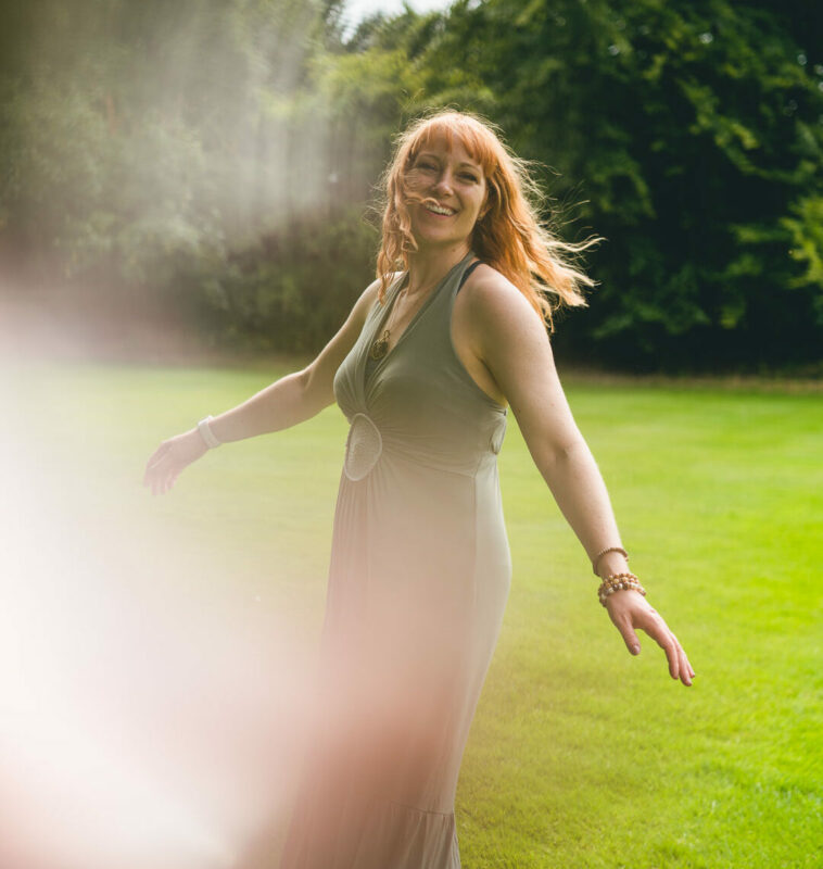 Ginny Marsh in a long green dress dancing outside in nature