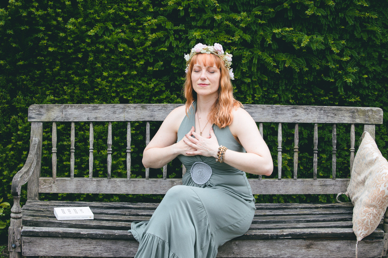 Portrait of Ginny Marsh wearing a green dress and flower crown, sitting on a bench. Branding shoot for Gorgeous You Retreats